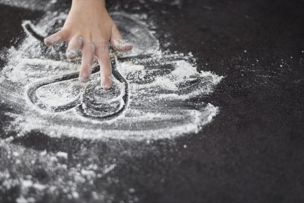 Close up girl s hand drawing heartshape flour