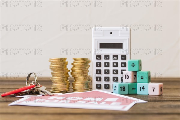 Close up home sale icon with key stacked coins calculator math blocks