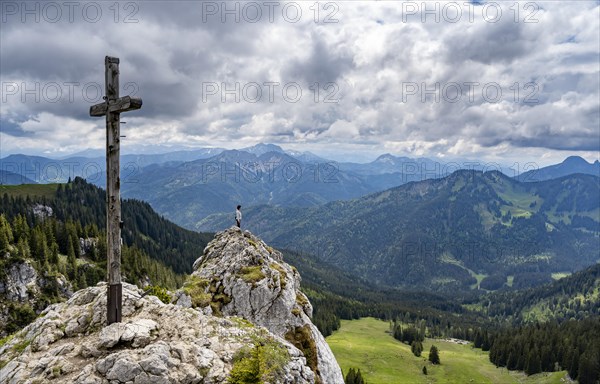 Mountaineer at the summit of Taubenstein with summit cross