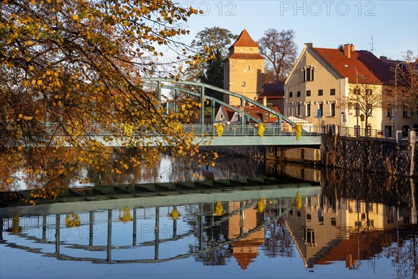 Autumnal coloured trees with iron bridge over the river Maltsch with the city wall of the historical old town of Ceske Budejovice