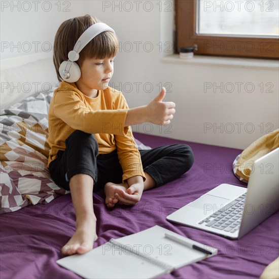 Boy sitting bed learning thumbs up