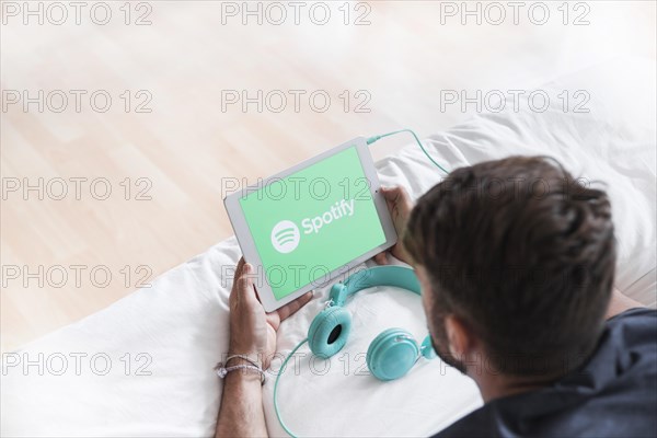 Young man holding modern device with spotify app