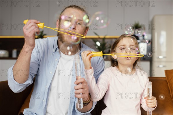 Front view father daughter playing with soap bubbles