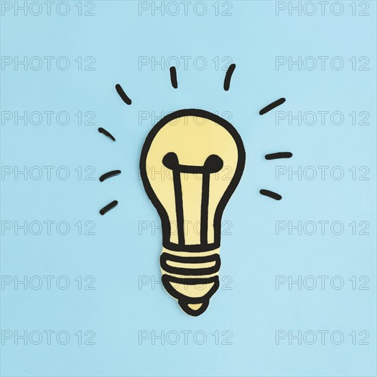 Illuminated paper cutout yellow light bulb blue background