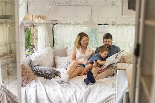 Long shot family looking through map caravan