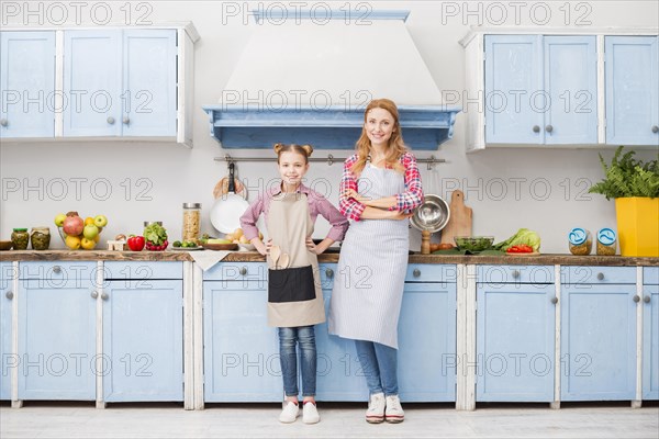 Portrait happy mother daughter apron standing kitchen