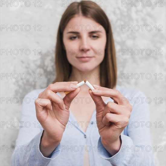 Portrait young woman breaking cigarette