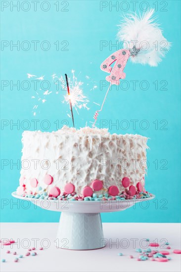 Fourth birthday cake with burning sparkler white surface