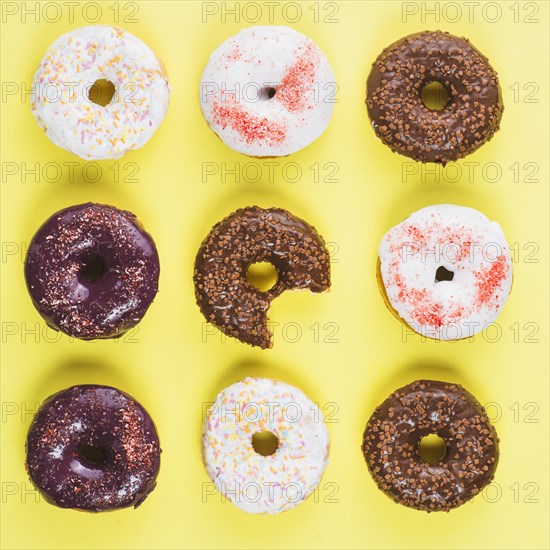 Brown white chocolate doughnuts with sprinkles missing bite