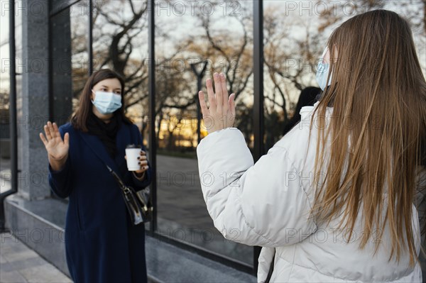 Girlfriends wearing masks wave