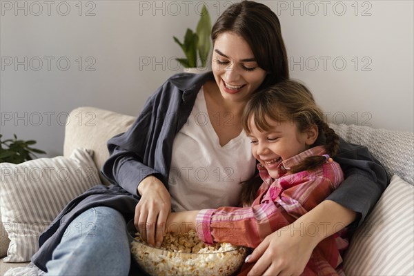 Mother daughter home eating popcorn