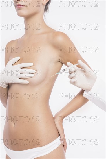 Plastic surgeon injecting woman breast