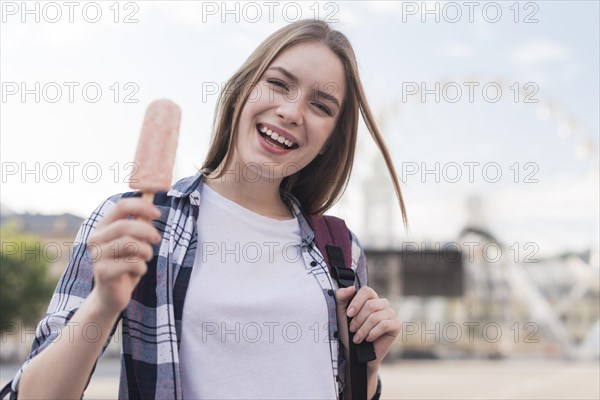 Portrait young happy woman holding popsicle amusement park