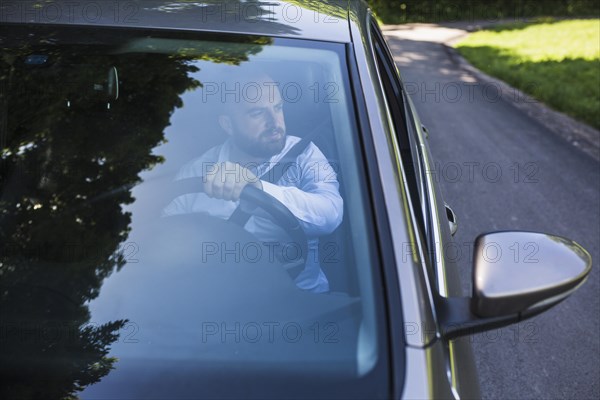 Man sitting inside car seen through windscreen