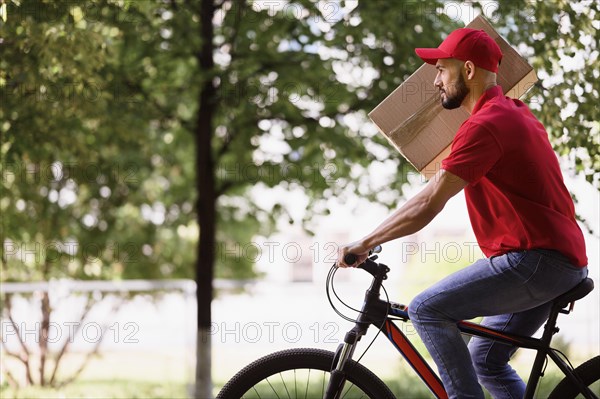 Side view delivery man carrying parcel bike