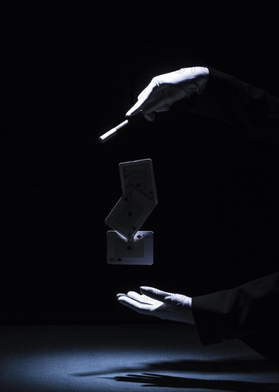 Magician performing trick with magic wand against black background