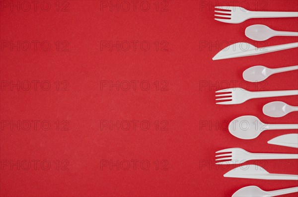 Plastic spoon fork arranged row bright red backdrop