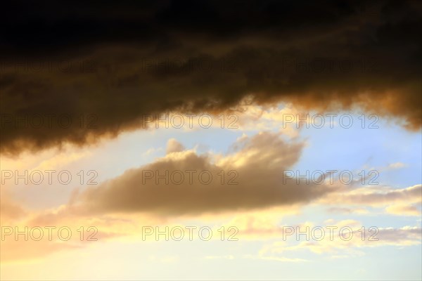 Cloudy sky at sunset. The sky is visible through a gap in the clouds. The image conveys a mood of an impending storm or bad weather