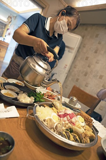 Korean woman pouring broth