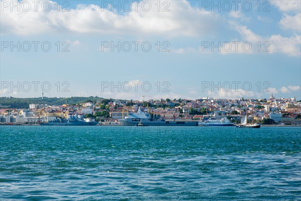 View of Tagus river with tourist boat and moored NATO warships in Lisbon