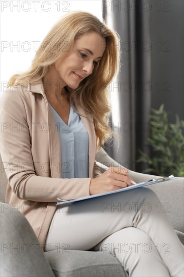 Mid shot woman therapist writing clipboard