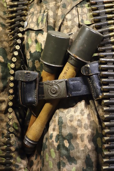 Close up of two WW2 stielhandgranaten tucked under pants belt of German SS soldier carrying machine gun ammunition belt