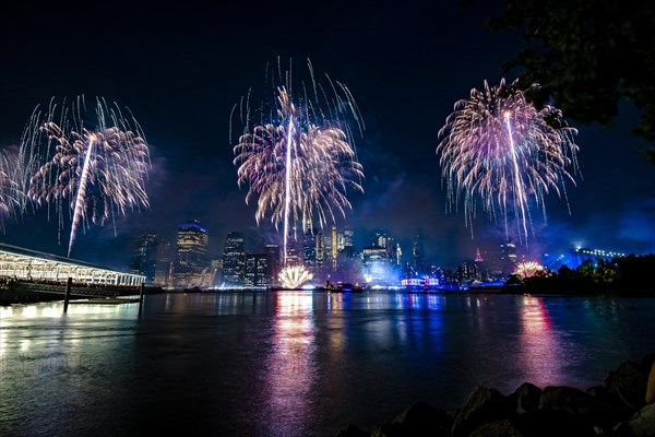 Independence day celebration in New York City with Macy's Fireworks in Lower Manhattan on East River and Brooklyn Bridge