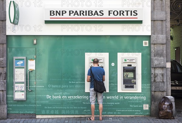 Man collecting money at cash dispenser of the BNP Paribas Fortis bank