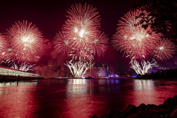 Independence day celebration in New York City with Macy's Fireworks in Lower Manhattan on East River and Brooklyn Bridge