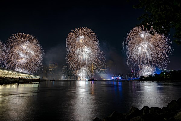 Independence day celebration in New York City with Macy's Fireworks in Lower Manhattan on East River and Brooklyn Bridge