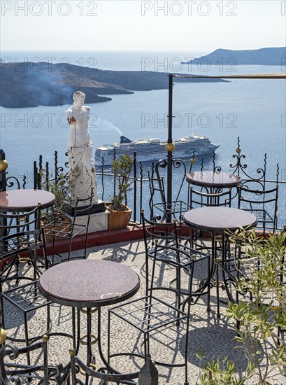 View of sea and cruise ship from terrace with chairs and table