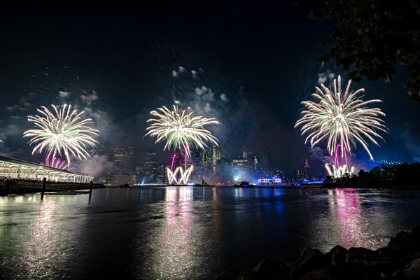 Independence day celebration in New York City with Macy's Fireworks in Lower Manhattan on East River and Brooklyn Bridge