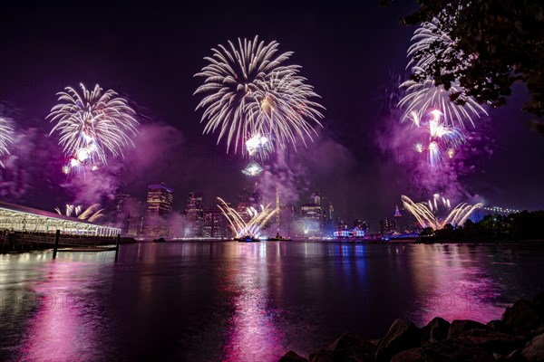 Independence day celebration in New York City with Macy's Fireworks in Lower Manhattan on East River and Brooklyn Bridge