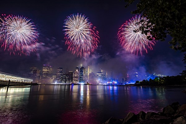 Independence day celebration in New York City with Macy's Fireworks in Lower Manhattan on East River and Brooklyn Bridge