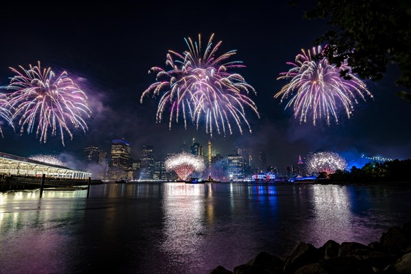 Independence day celebration in New York City with Macy's Fireworks in Lower Manhattan on East River and Brooklyn Bridge