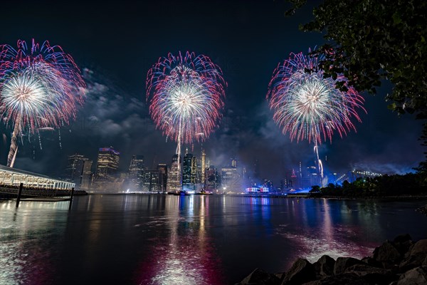 Independence day celebration in New York City with Macy's Fireworks in Lower Manhattan on East River and Brooklyn Bridge