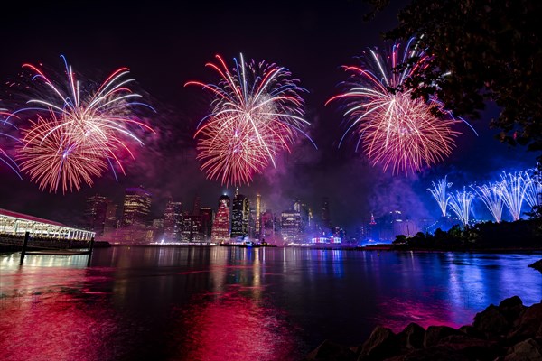 Independence day celebration in New York City with Macy's Fireworks in Lower Manhattan on East River and Brooklyn Bridge