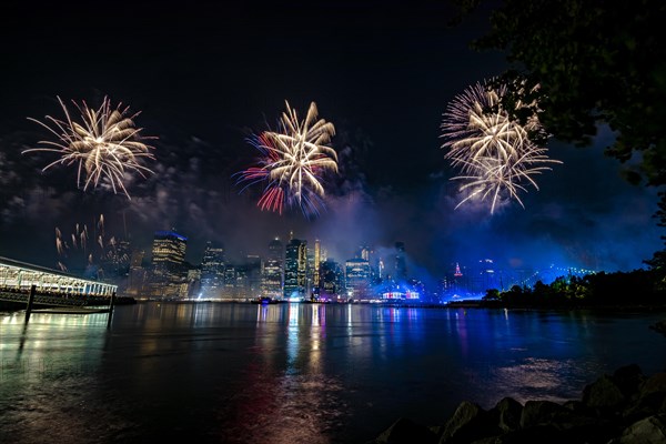 Independence day celebration in New York City with Macy's Fireworks in Lower Manhattan on East River and Brooklyn Bridge