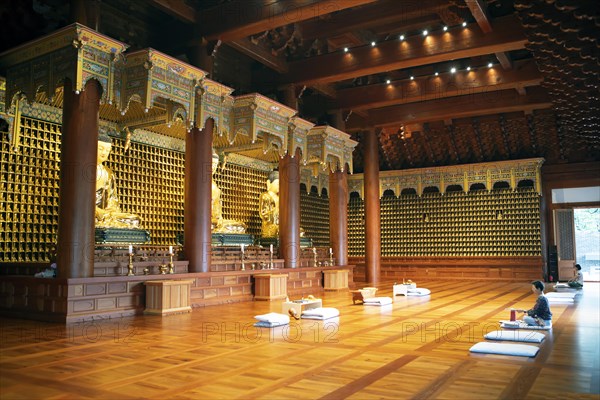 Korean woman praying at the golden Buddha statues in the temple