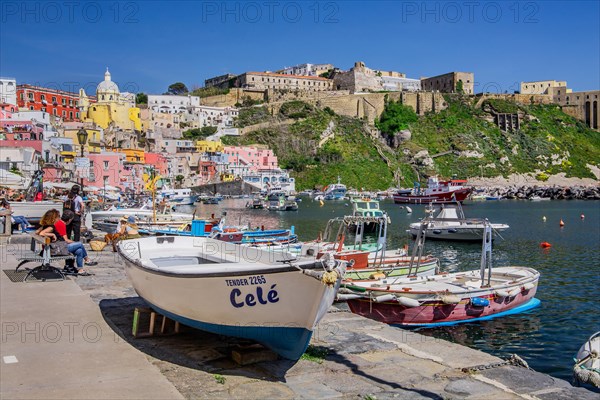 Shore path with fishing boats and fishing harbour of the fishing village Corricella and the fortress Terra Murata