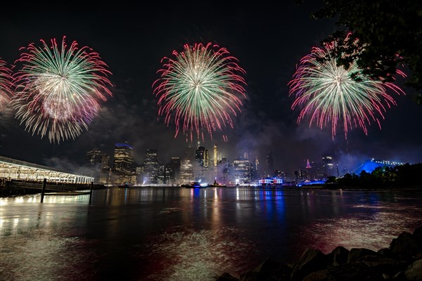 Independence day celebration in New York City with Macy's Fireworks in Lower Manhattan on East River and Brooklyn Bridge