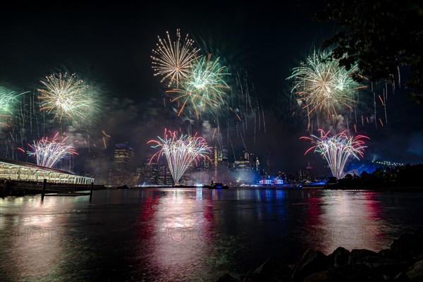 Independence day celebration in New York City with Macy's Fireworks in Lower Manhattan on East River and Brooklyn Bridge