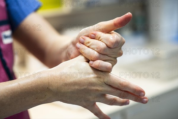 A doctor prepares for an operation and sterilises her hands with disinfectant