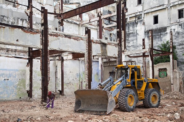 Workers and bulldozer renovating old house in Havana