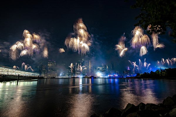 Independence day celebration in New York City with Macy's Fireworks in Lower Manhattan on East River and Brooklyn Bridge