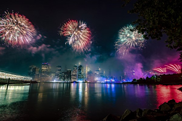 Independence day celebration in New York City with Macy's Fireworks in Lower Manhattan on East River and Brooklyn Bridge