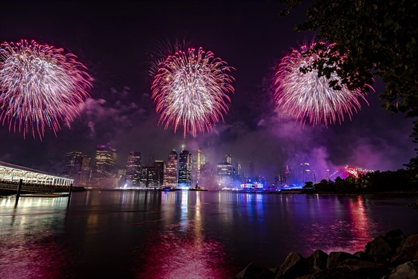 Independence day celebration in New York City with Macy's Fireworks in Lower Manhattan on East River and Brooklyn Bridge