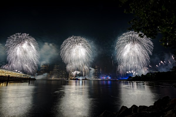 Independence day celebration in New York City with Macy's Fireworks in Lower Manhattan on East River and Brooklyn Bridge