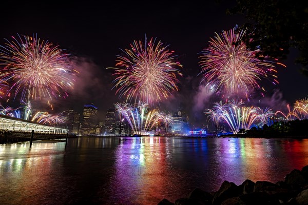 Independence day celebration in New York City with Macy's Fireworks in Lower Manhattan on East River and Brooklyn Bridge