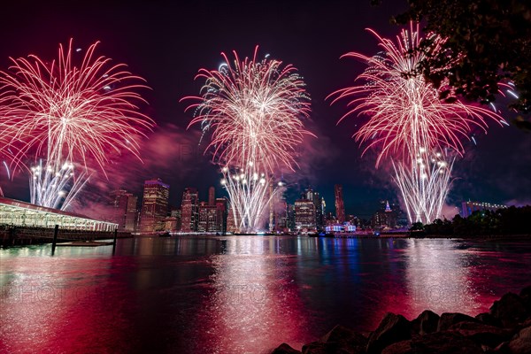 Independence day celebration in New York City with Macy's Fireworks in Lower Manhattan on East River and Brooklyn Bridge